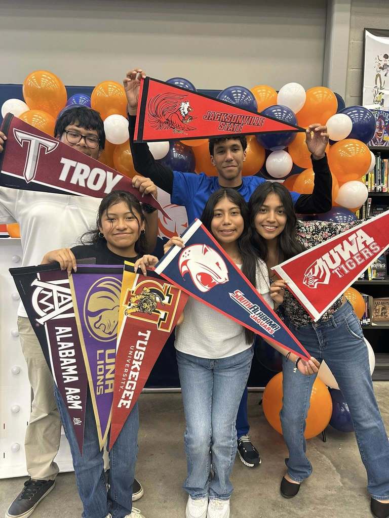 Students hold up pennant flags to colleges they have been accepted to. 