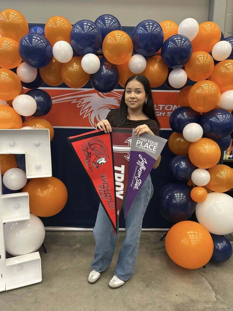 Students hold up pennant flags to colleges they have been accepted to. 