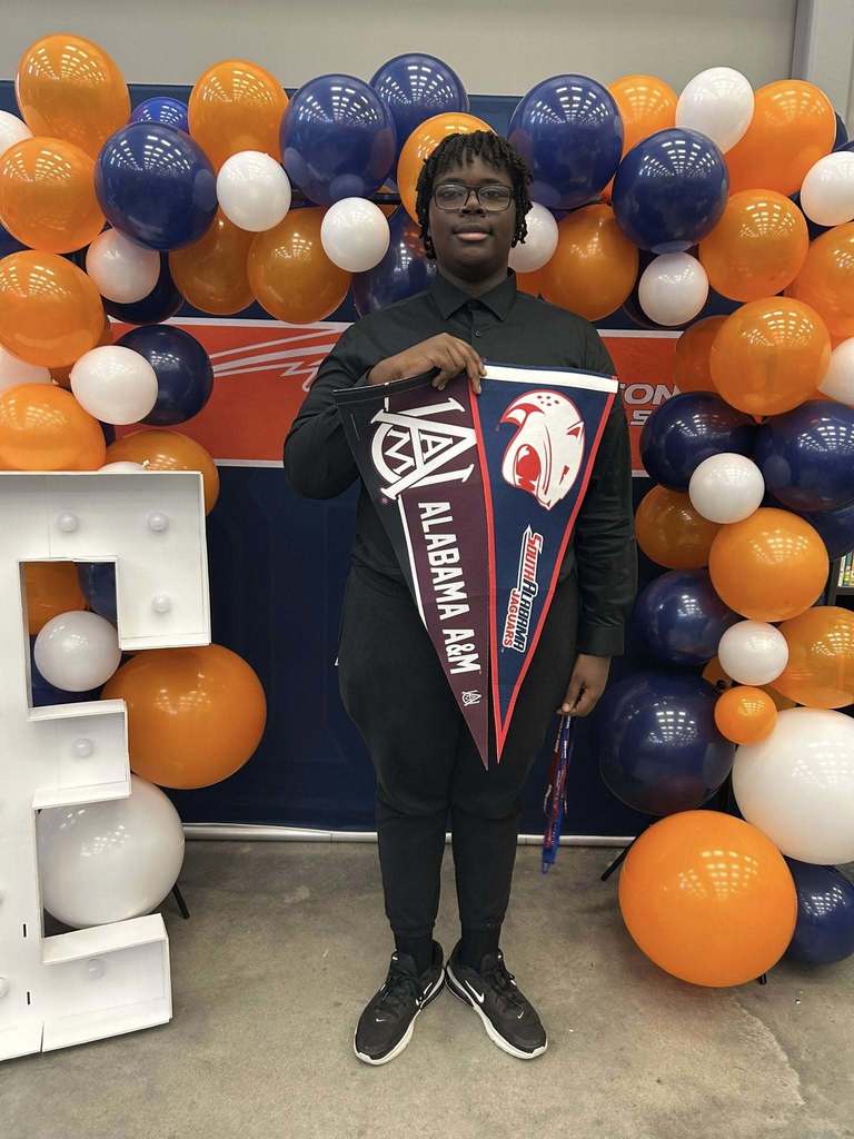Students hold up pennant flags to colleges they have been accepted to. 
