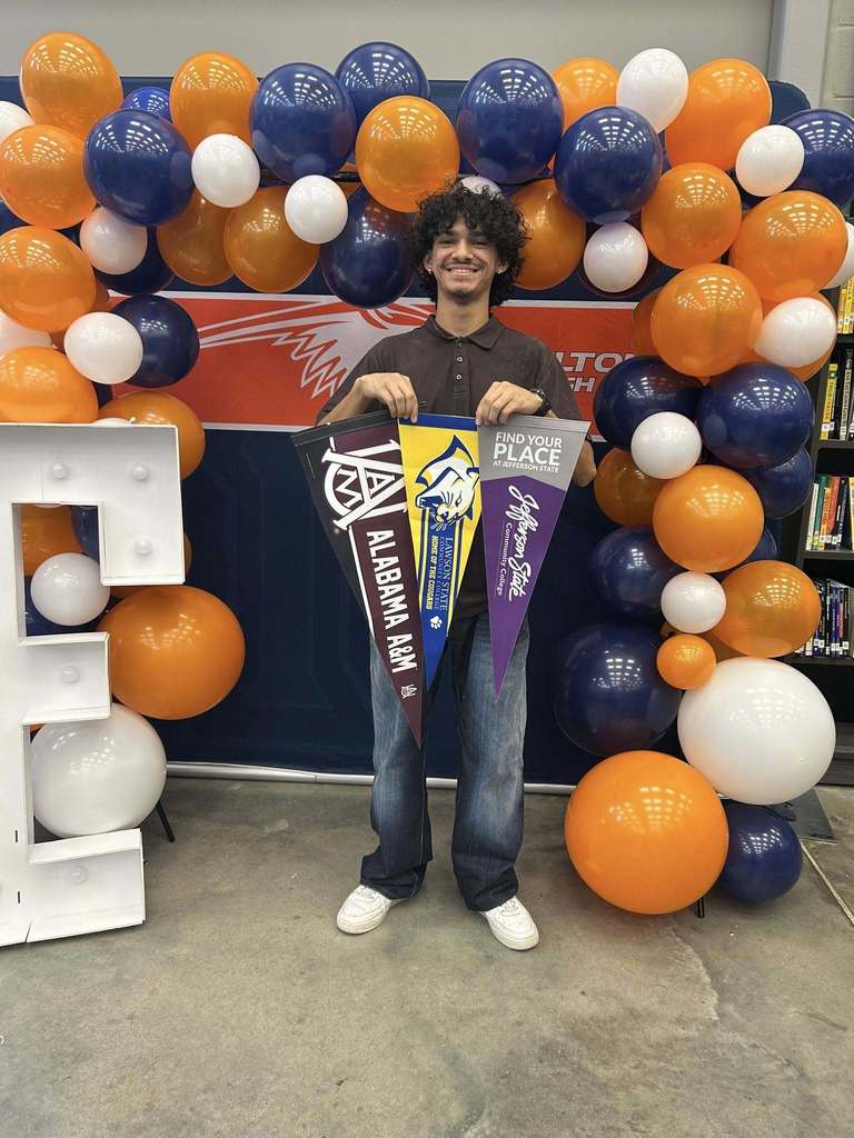 Students hold up pennant flags to colleges they have been accepted to. 