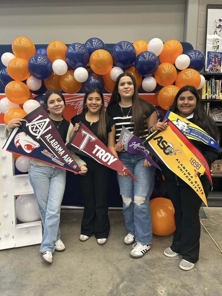 Students hold up pennant flags to colleges they have been accepted to. 