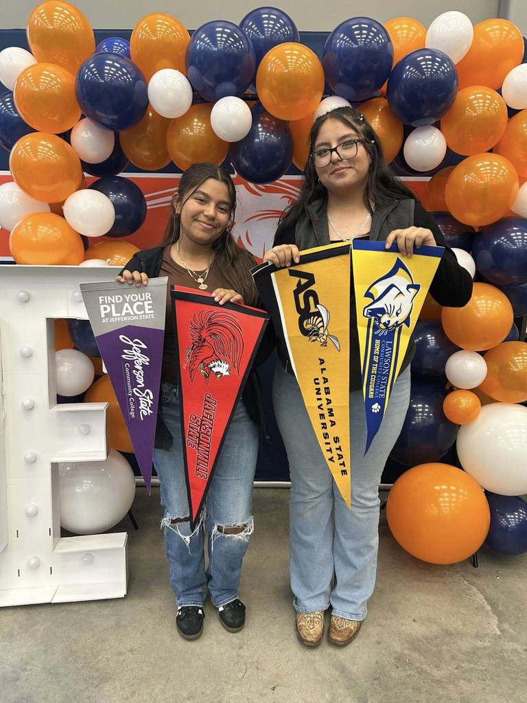 Students hold up pennant flags to colleges they have been accepted to. 