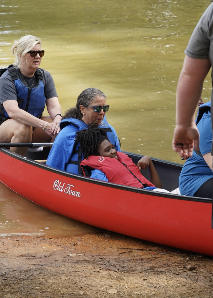 Four people sit in a canoe on shore.