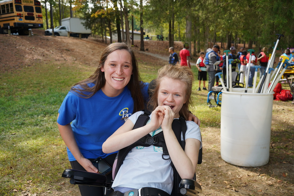 A student and teacher pose for a picture in a wooded area.