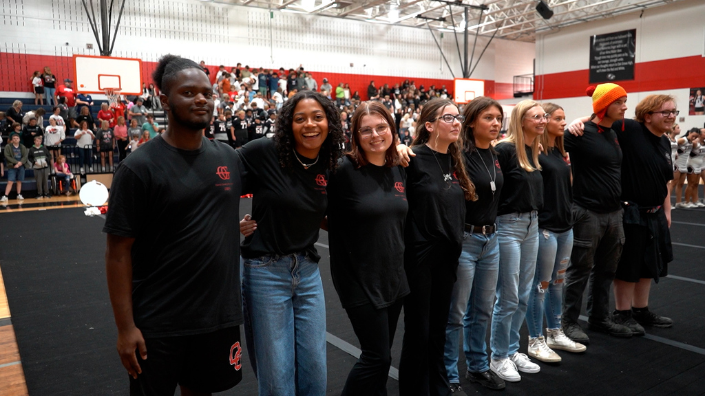 Students stand together and hug in a school gym.