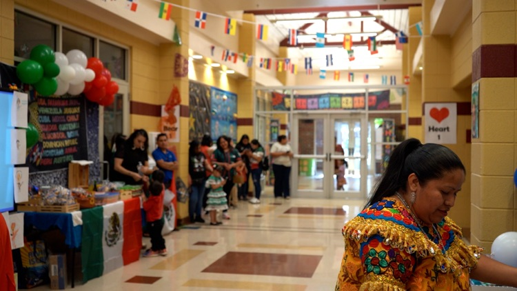 Adults stand in a school hallway that is filled with displays for Hispanic Heritage Month