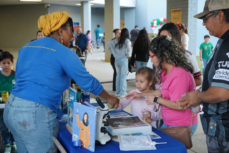 An employee from the McWane Science Center shows a family a fossil during a Hispanic Heritage Month festival.