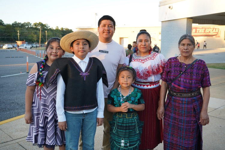 A family stands together at a Hispanic Heritage Festival and smiles.