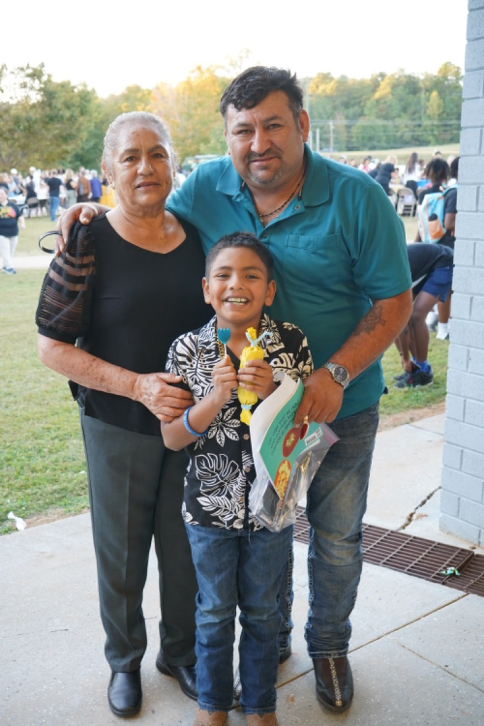 A family stands together and smiles while attending a Hispanic Heritage Festival.