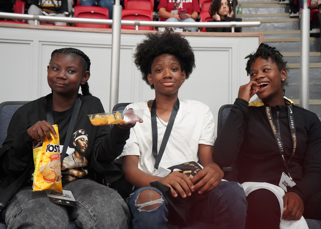 Three students enjoy snacks during a basektball game.