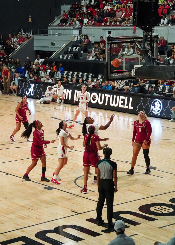Photo of the Alabama Crimson Tide Women's Basketball team taking on Florida State at the Boutwell Auditorium. They players are looking up at the ball as it is about to go in the basket.