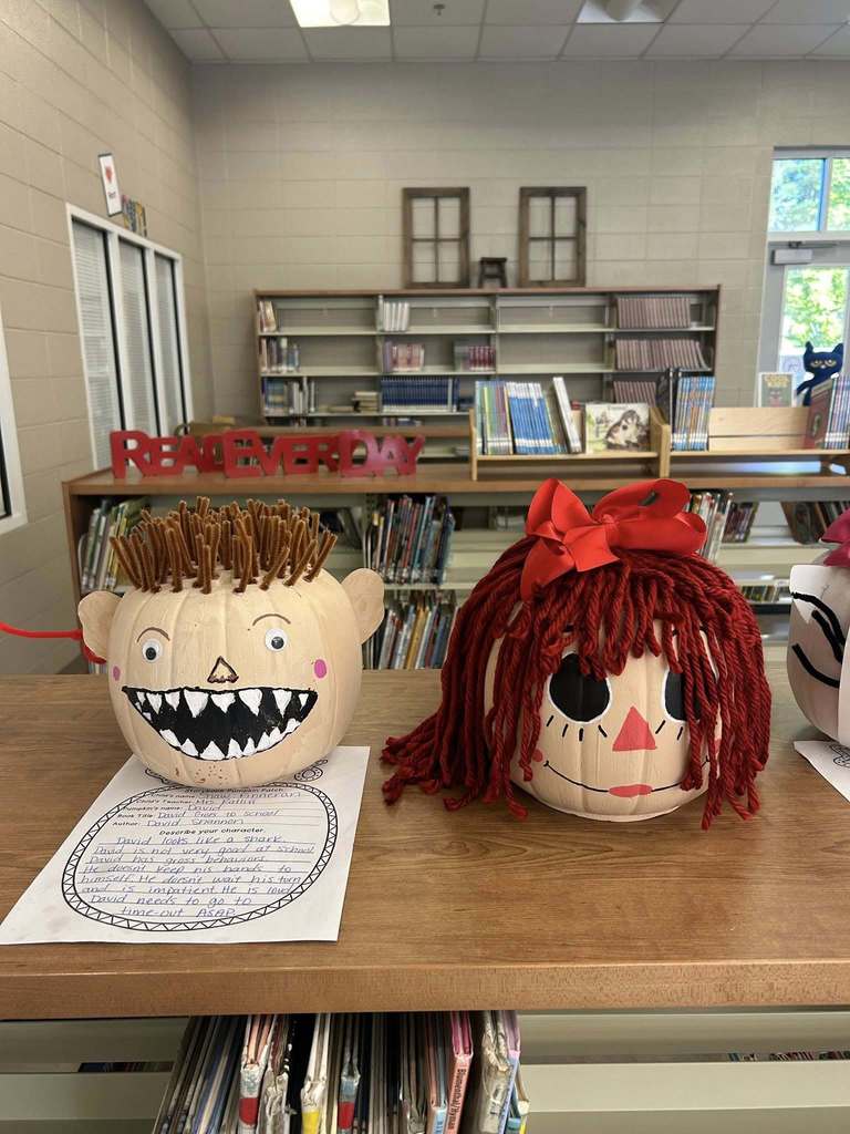 Pumpkins decorated like book characters sit on the shelves of a library.