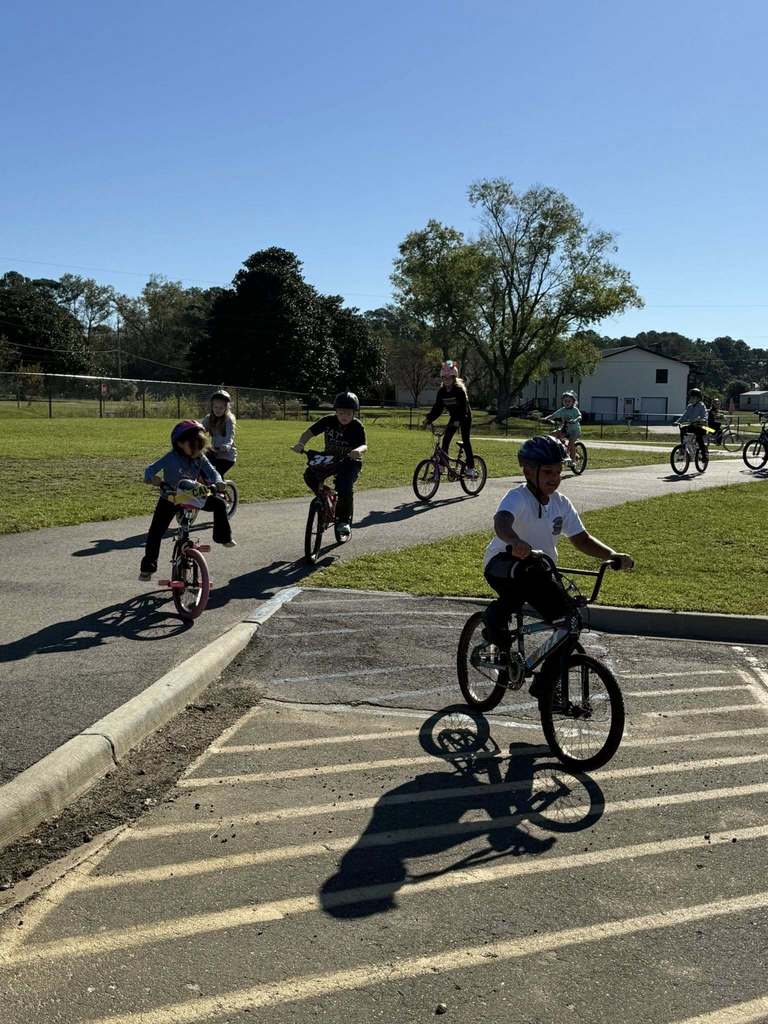 Students ride bicycles on a parking lot.