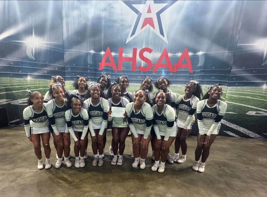 Clay-Chalkville High School cheerleaders stand together for a photo in front of a sign that says "AHSAA"