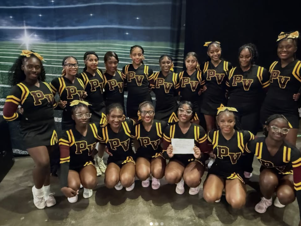 Pinson Valley cheerleaders pose together for a photo. One cheerleader in the middle holds a piece of paper in her hands.