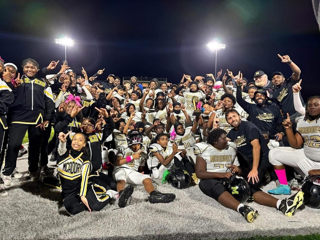 McAdory Middle School cheerleaders and football players pose together on a football field.