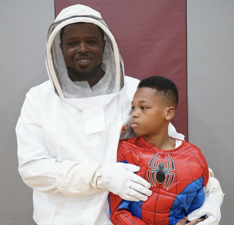 A man in a fencing costume poses with a boy in a Spider-Man costume
