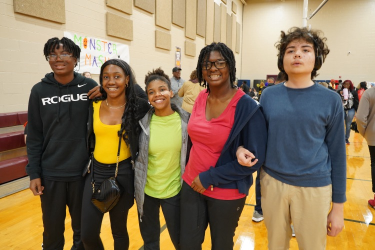 A group of students stand together and pose for a photo in a school gym.