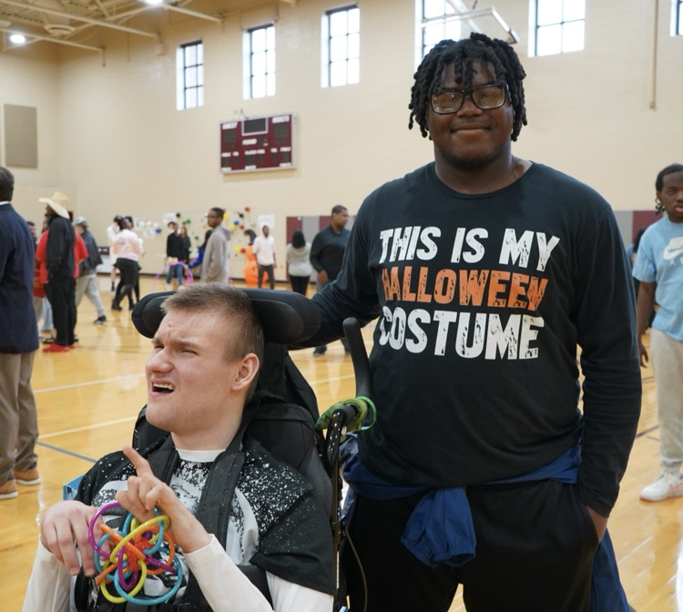 Two students pose together for a photo in a school gym  