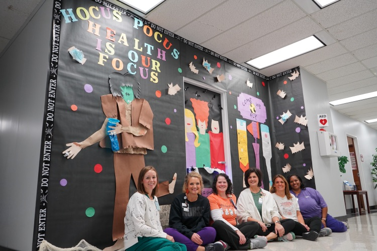 JEFCOED board employees sit on the ground in front of their Halloween display. 