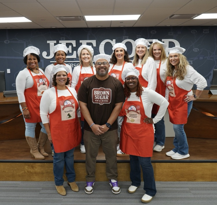 A group of board employees stand together for a photo. They’re dressed as spices  