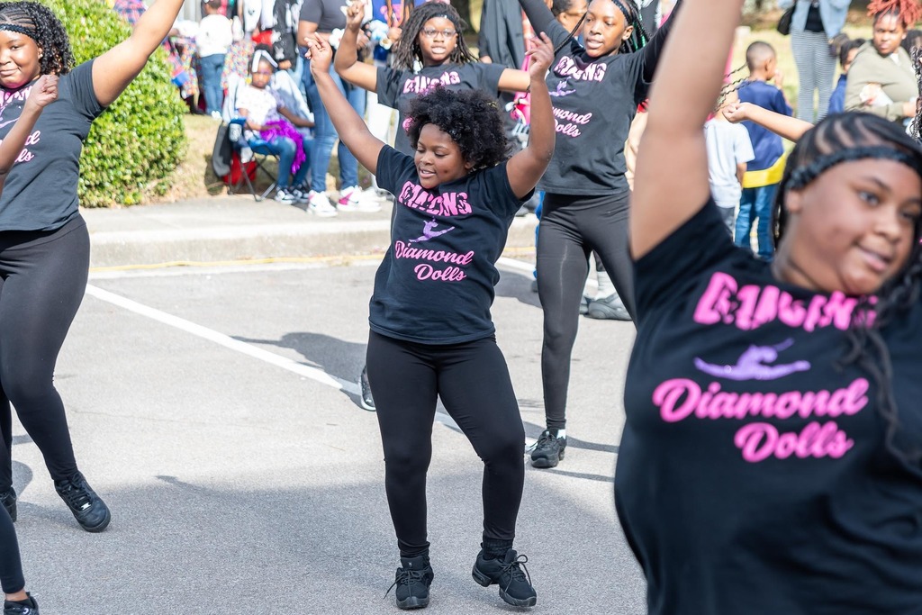 Members of the Diamond Dolls dance team perform in a parking lot.