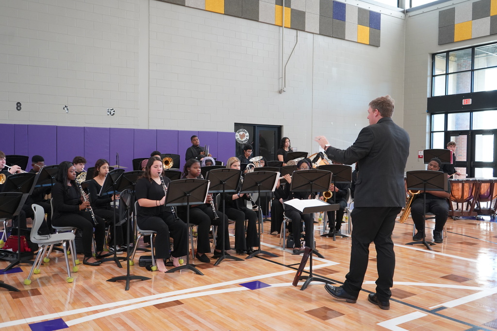Hueytown High School's band director leads band members as they perform in a school gym.