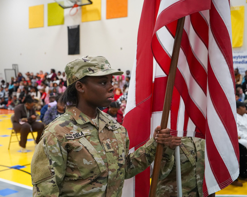 A member of the Spartans Battalion Leadership Academy holds the American flag. She is dressed in camouflage. 