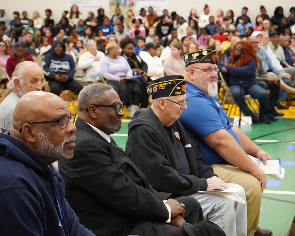 Veterans sit in a row at a Veterans Day program. 