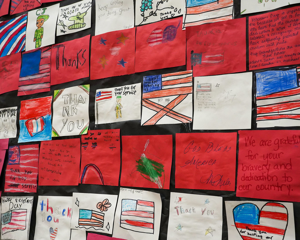A picture of a patriotic mural display. Each post-it shaped note is a message to a veteran. The notes together form the American flag. 