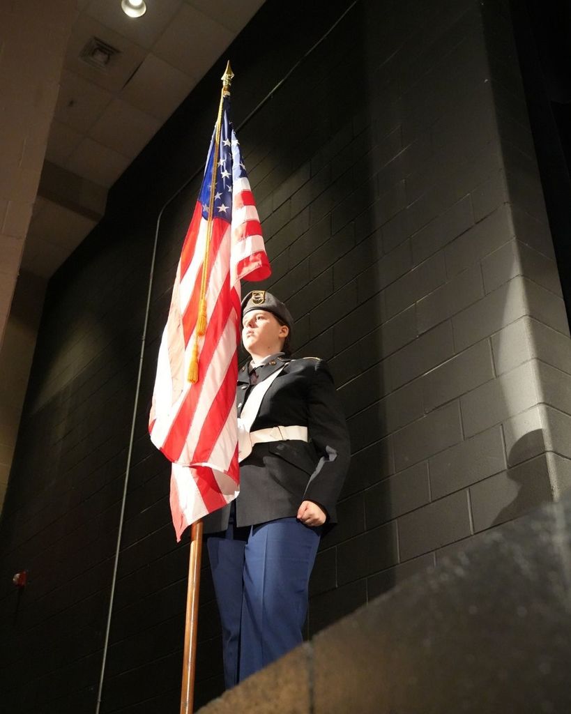 A student in a JROTC uniform holds an American flag.