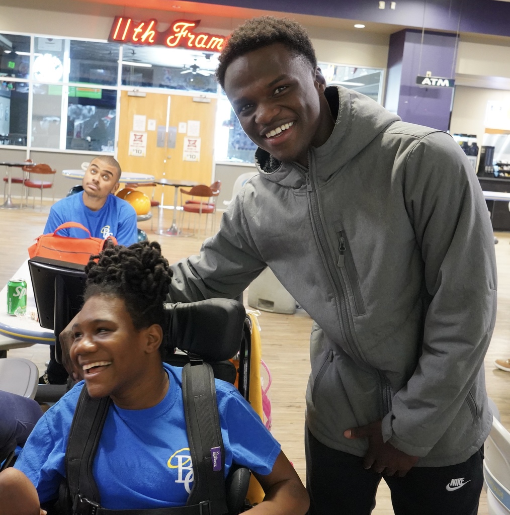 Two students smile together for a photo at a bowling alley.
