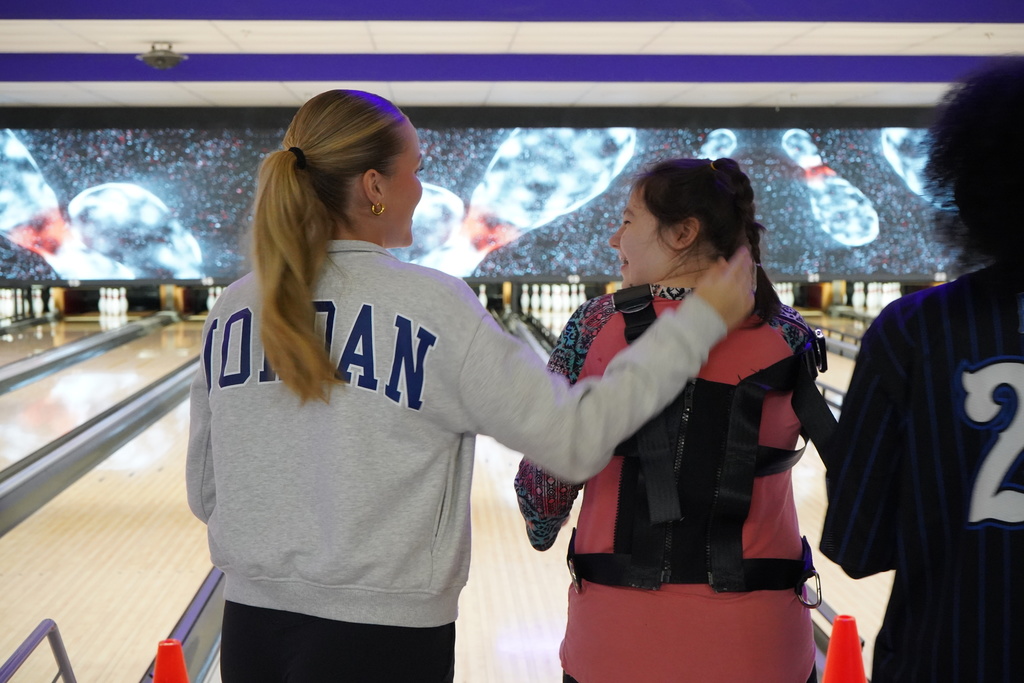 A student pats another student on the back while at the bowling alley.