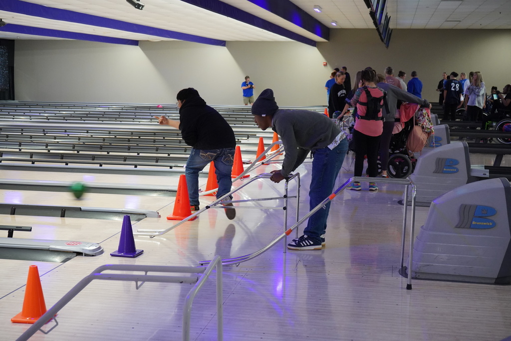 Students bowl at a bowling alley.