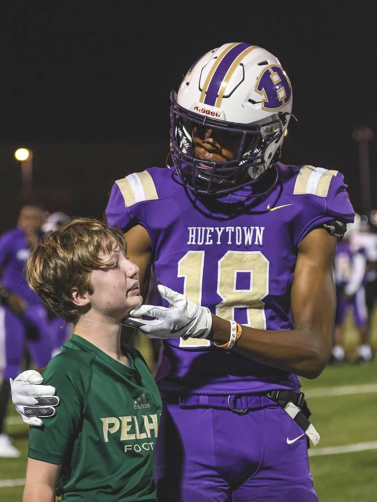 A Hueytown High School football player comforts the son of Pelham football's head coach on a football field.