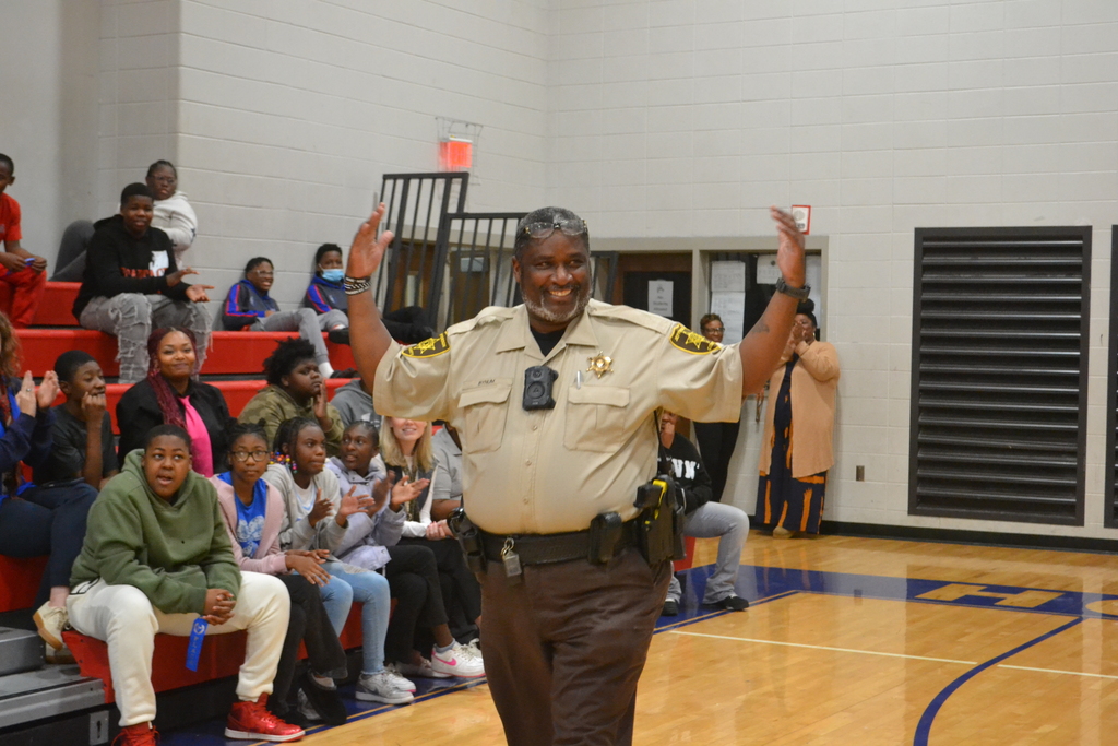 School Officer walking with his hands up as students cheer