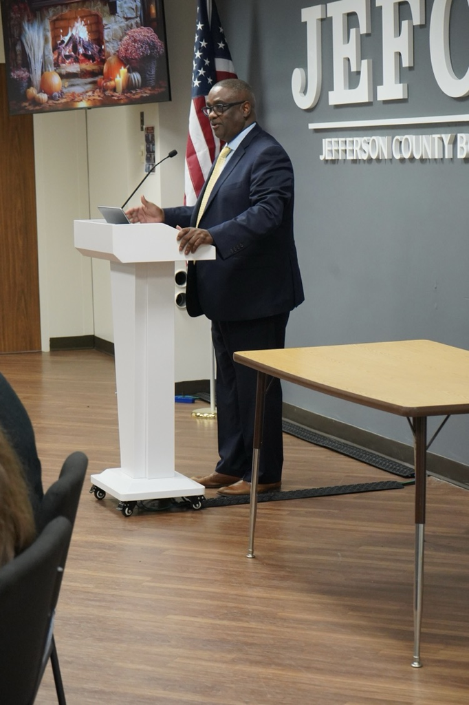 Dr. Gonsoulin talks to JEFCOED employees while he stands at a podium.