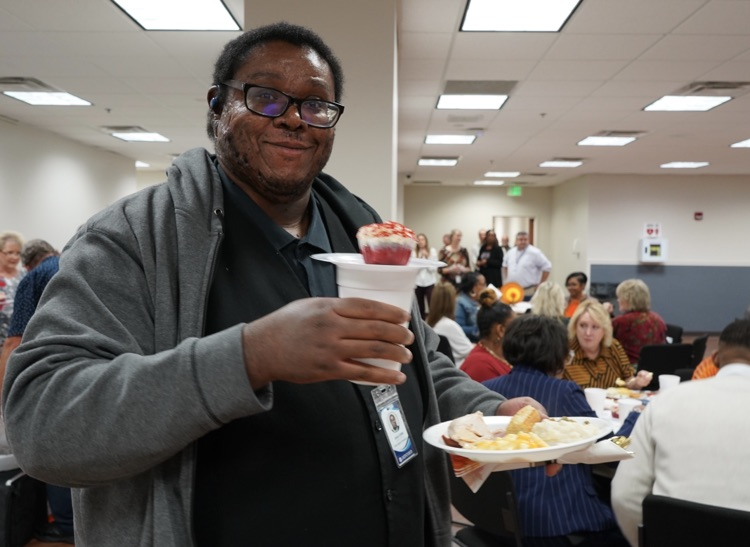A man smiles while holding a Thanksgiving meal at JEFCOED’s Thanksgiving lunch.