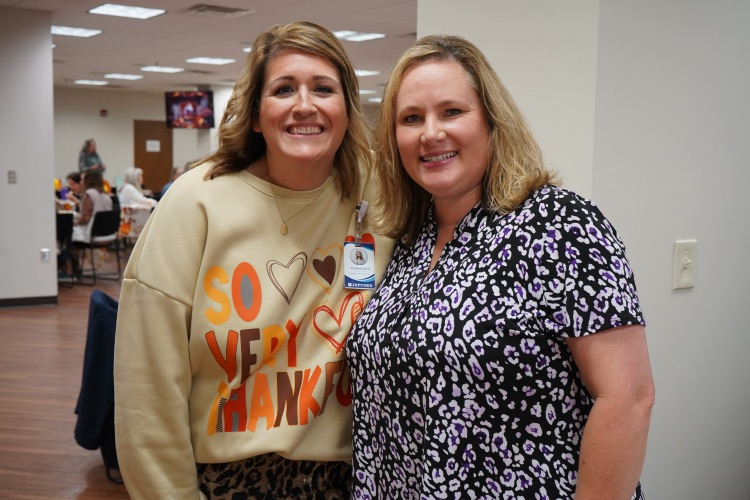 Two women stand together for a photo and smile.