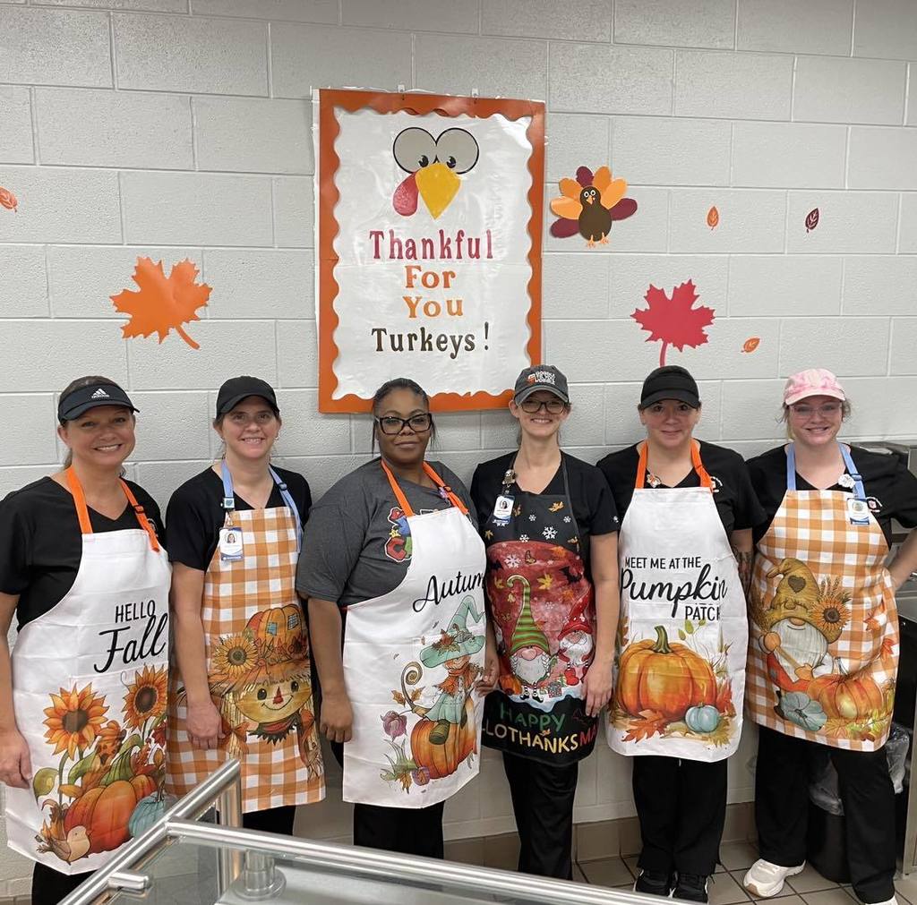 JEFCOED child nutrition employees stand together and smile for a photo inside a school They all wear fall themed aprons.