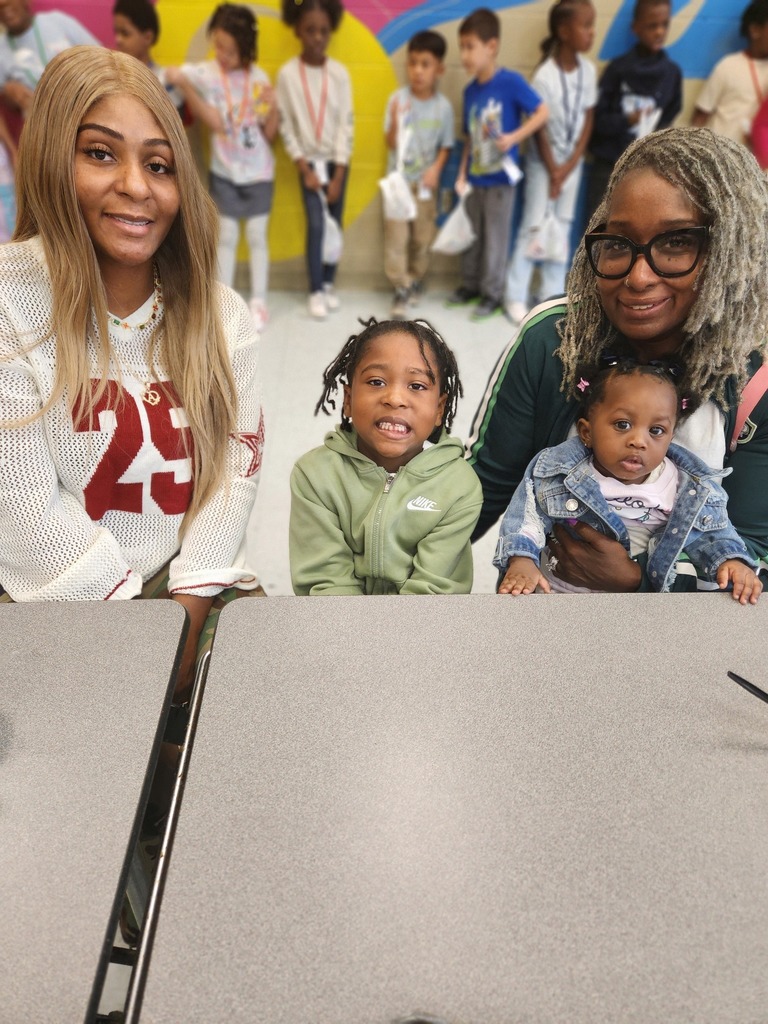 Two adults and two children smile for a photo while sitting at a lunchroom table.