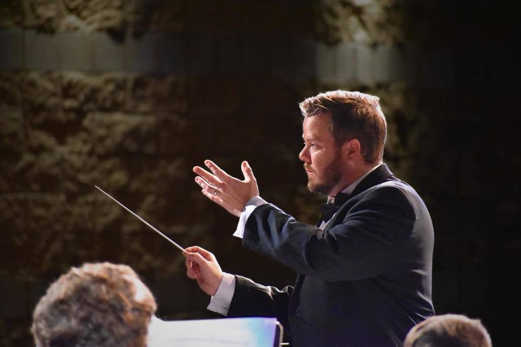Corner High School's band director leads the band during a performance in a school auditorium.