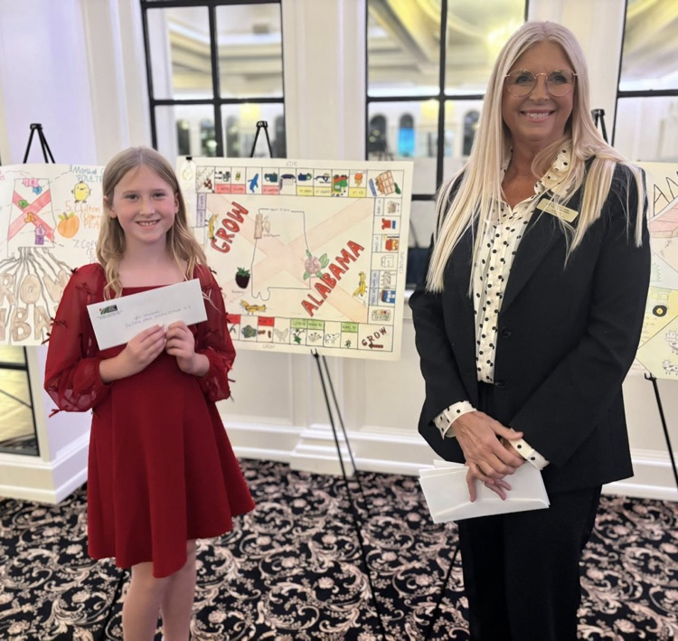 A woman and a girl stand together for a photo in front of a poster.