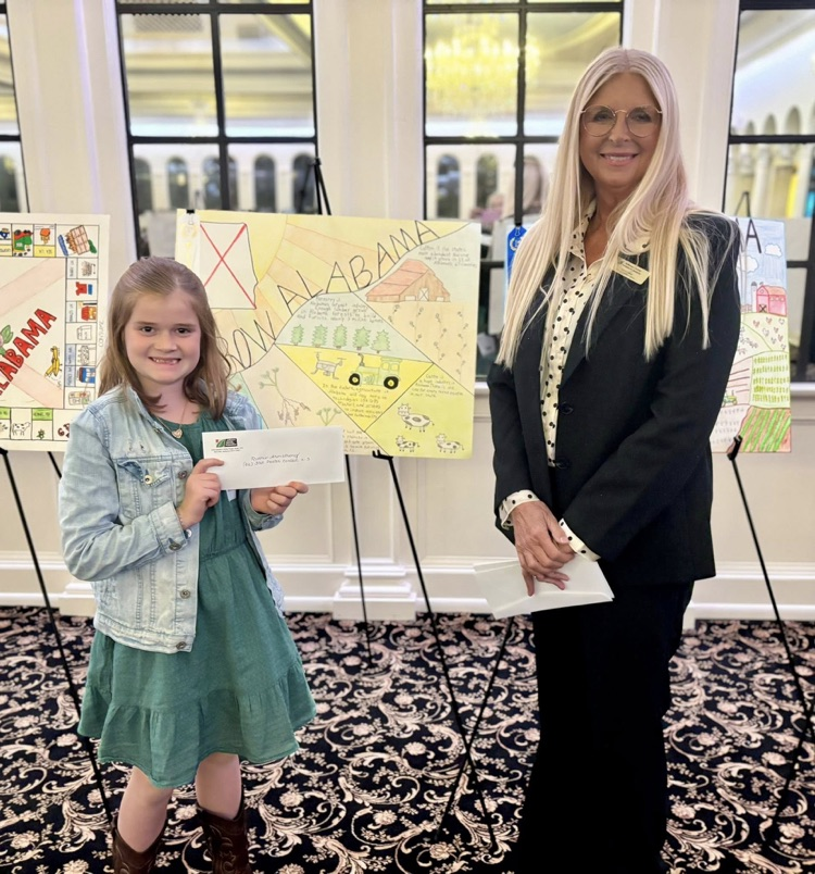 A woman and a girl stand together for a photo in front of a poster.
