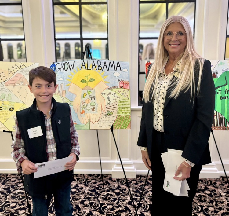 A woman and a boy stand together for a photo in front of a poster.