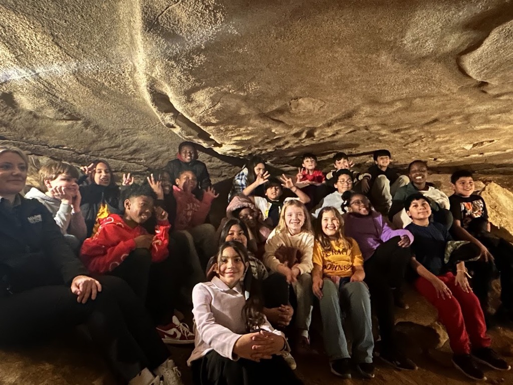 A group of students smile while sitting in a cave.