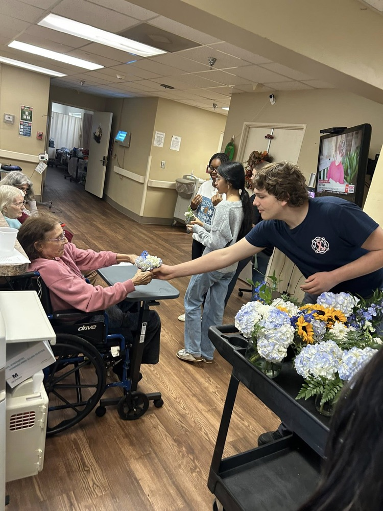 McAdory High School students hand flowers out to residents in a retirement community.