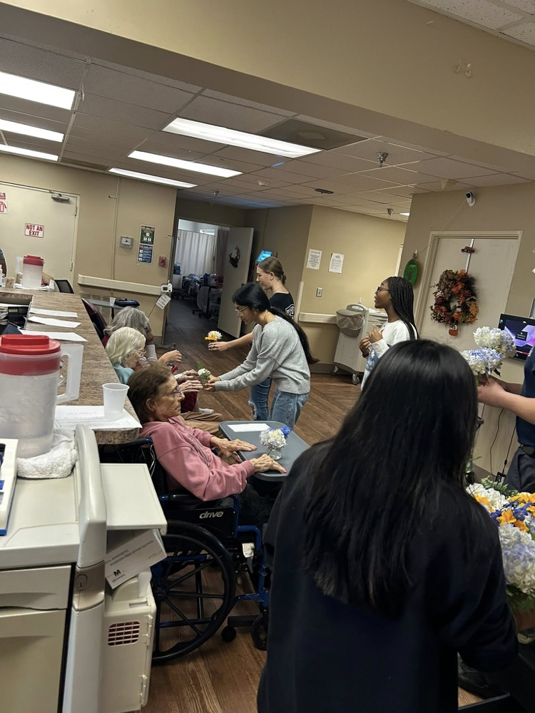 McAdory High School students hand flowers out to residents in a retirement community.