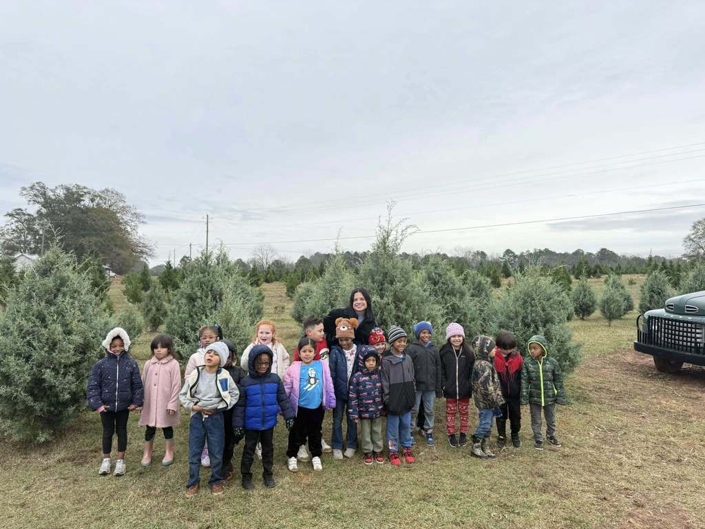 Students and an adult stand together for a photo and smile.