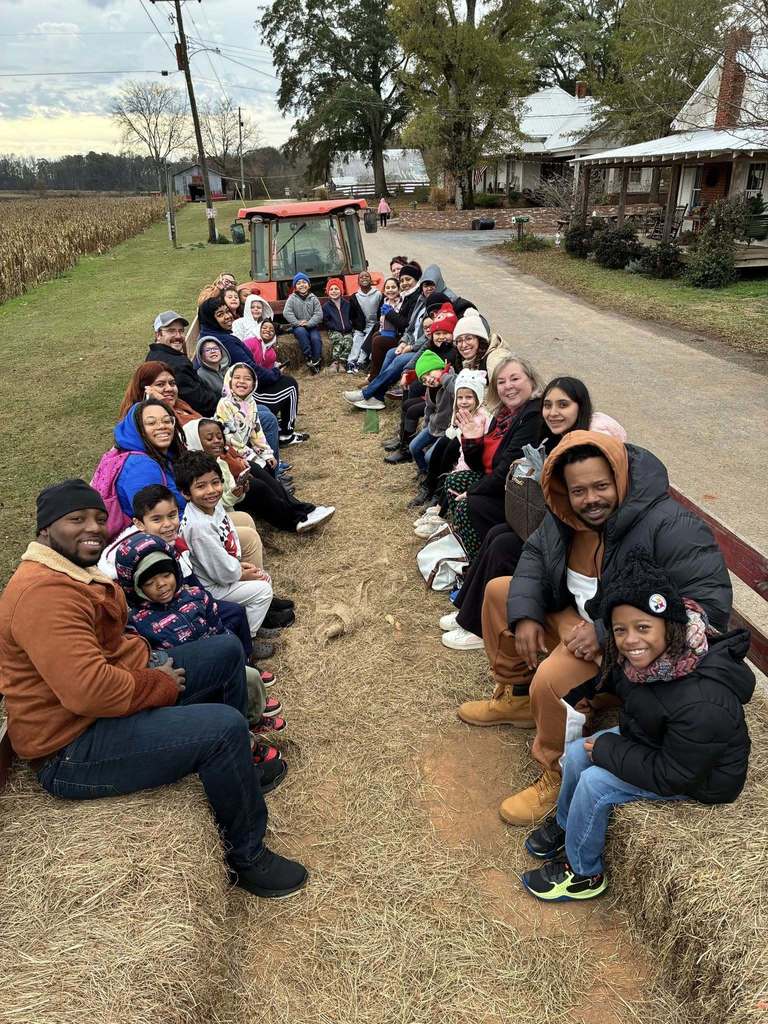 Children and adults smile for a photo while on a hay ride.
